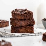 a stack of three flourless vegan protein brownies on wire cooling rack