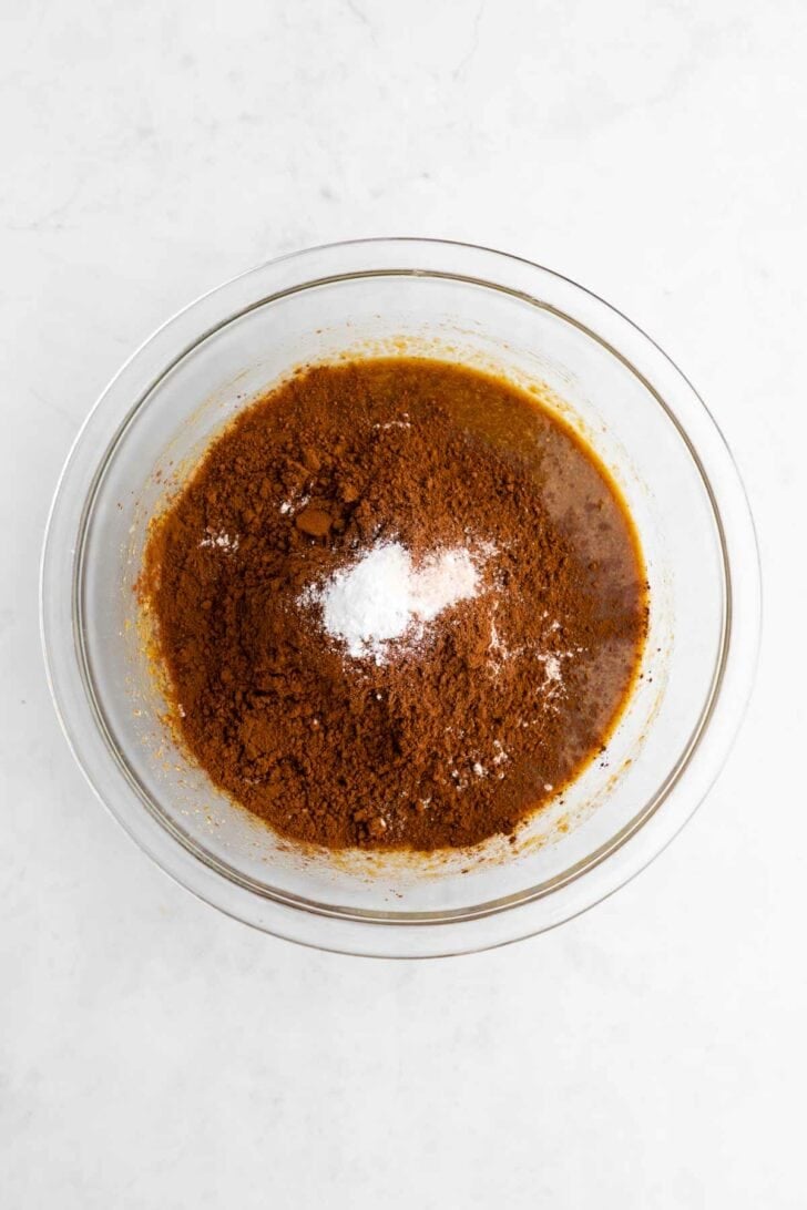 wet and dry ingredients in a glass bowl for vegan banana brownies