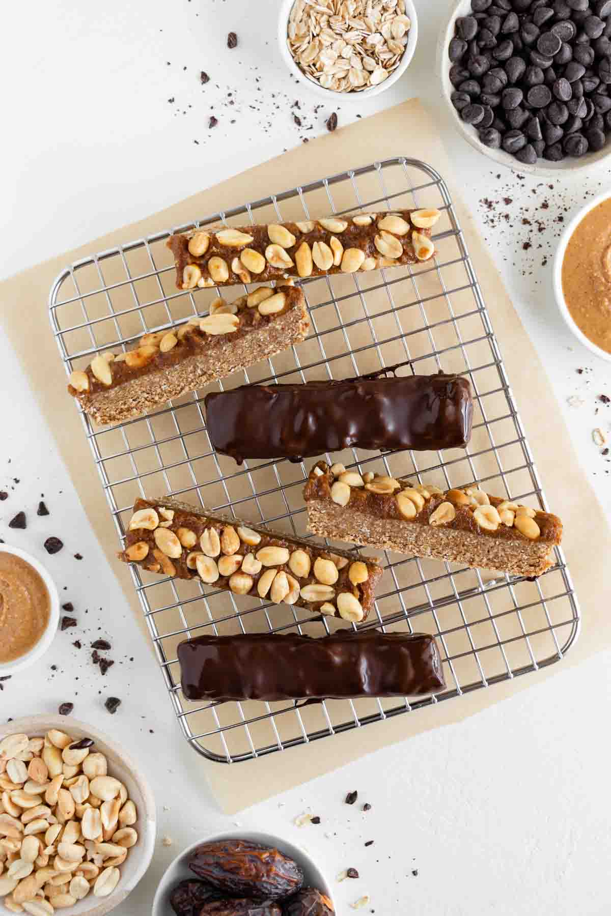 vegan snickers bars with nougat, date caramel, and chocolate on a wire cooling rack