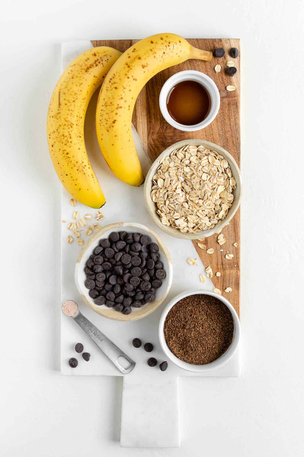 a white marble board topped with oats, vanilla, ground flaxseed, chocolate, and fruit