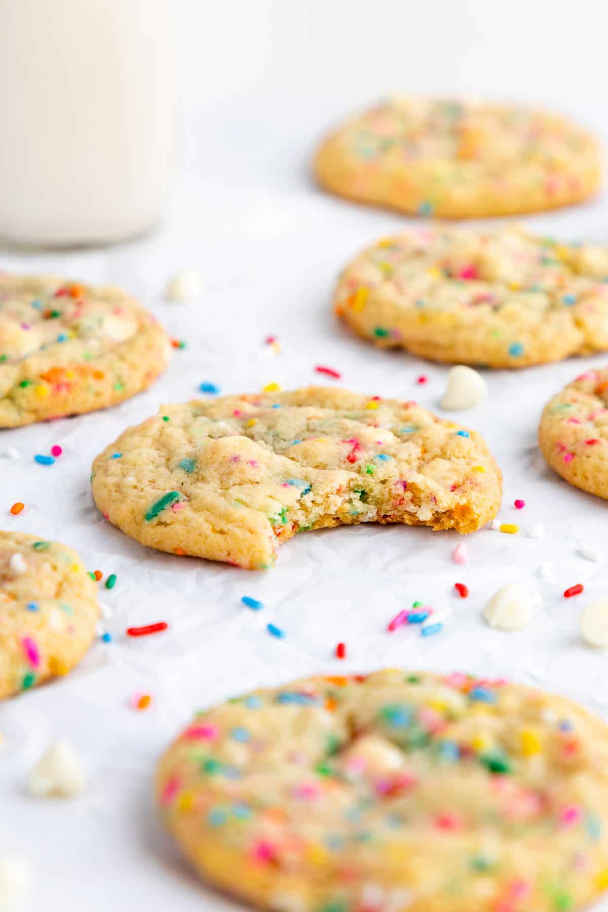 a hand holding a giant vegan birthday cake cookie with sprinkles, white chocolate chips, and chocolate chips