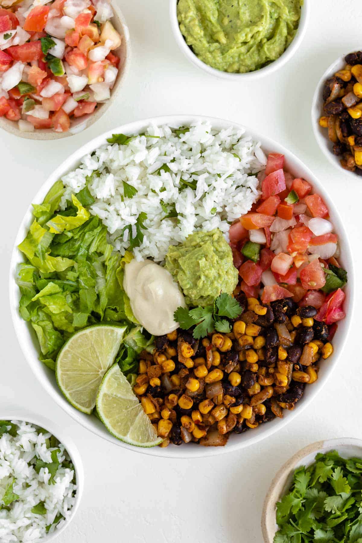 vegan burrito bowl with black beans, corn, cilantro lime rice, pico de gallo, lettuce, guacamole, and cashew sour cream