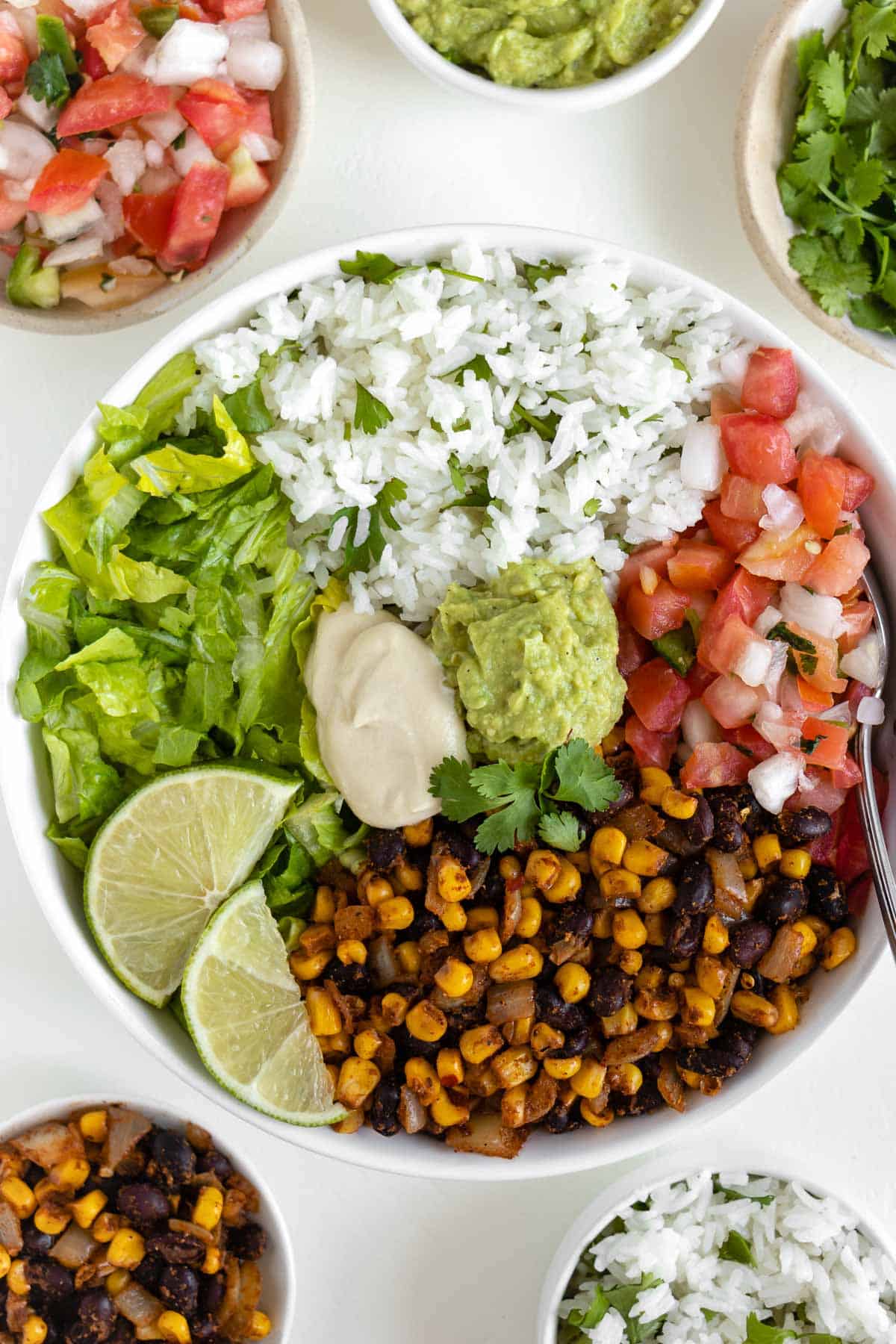 vegan burrito bowl with black beans, corn, cilantro lime rice, pico de gallo, lettuce, guacamole, and cashew sour cream