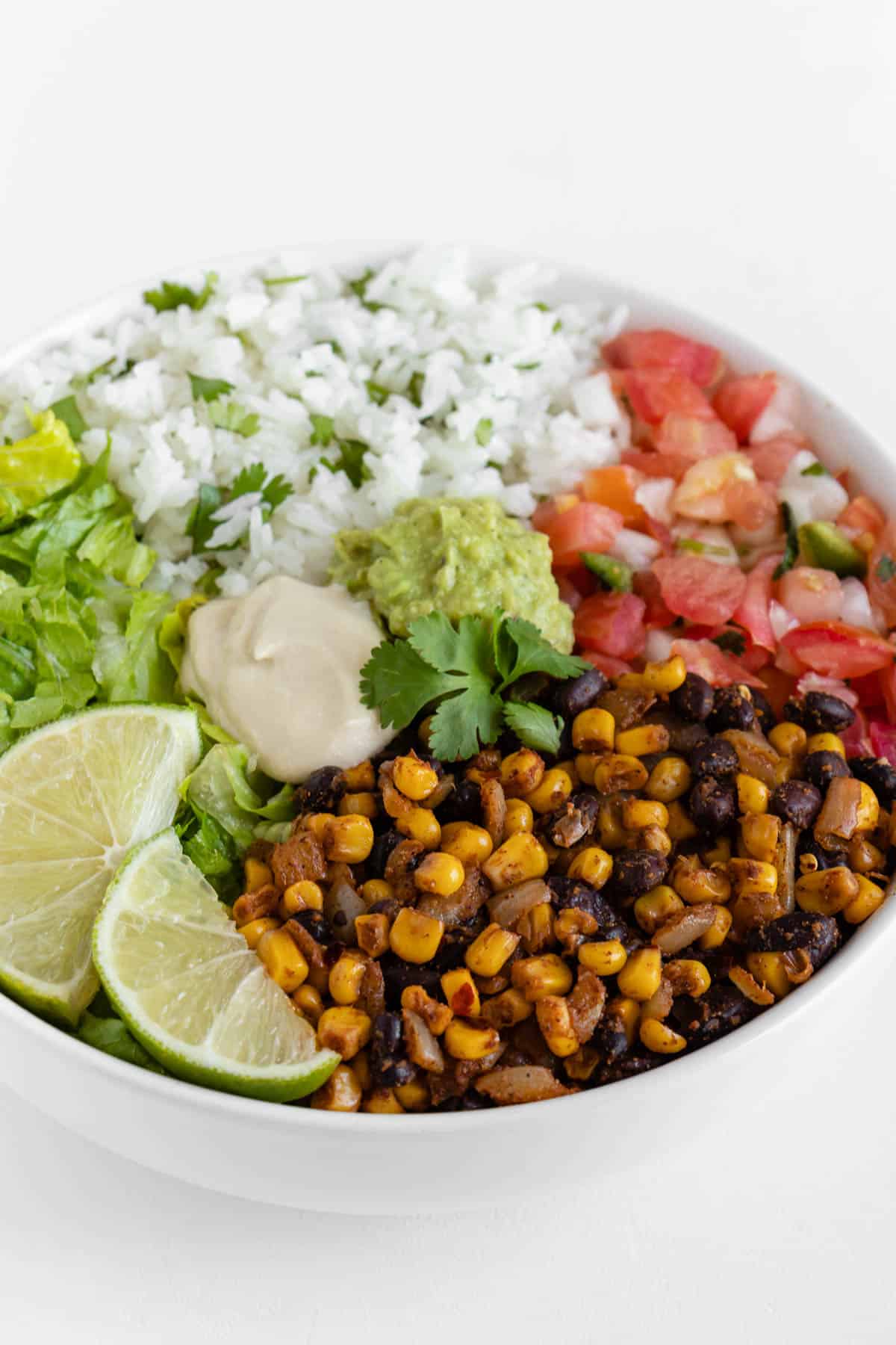 a vegan burrito bowl with cilantro lime rice, corn and beans, pico de gallo, guacamole, and romaine lettuce