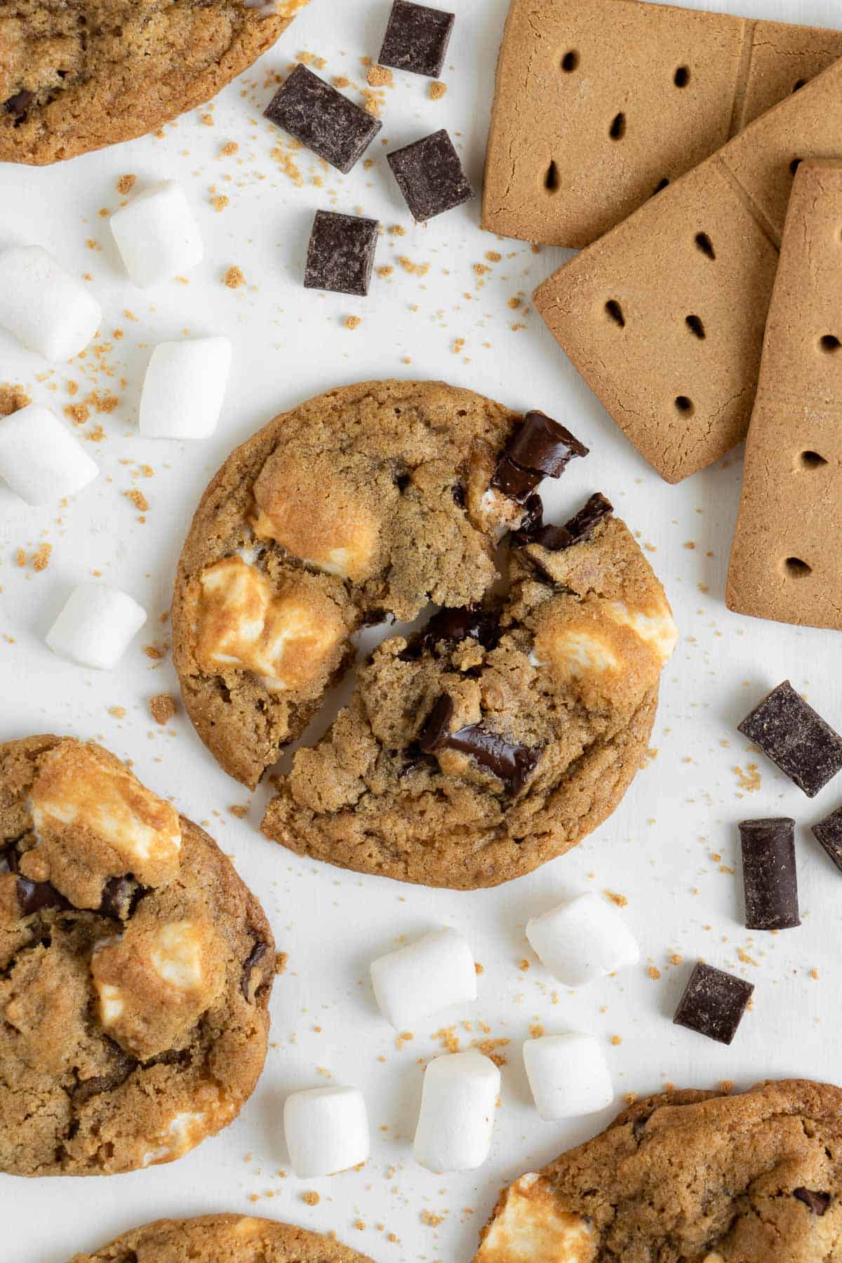 a vegan s'mores cookie surrounded by mini marshmallows, vegan graham crackers, and chocolate chunks