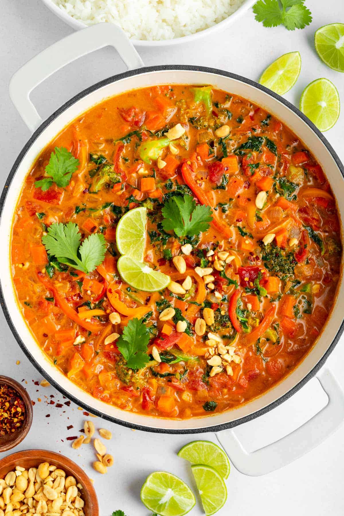 a wooden board topped with two bowls fo vegan thai red curry and rice