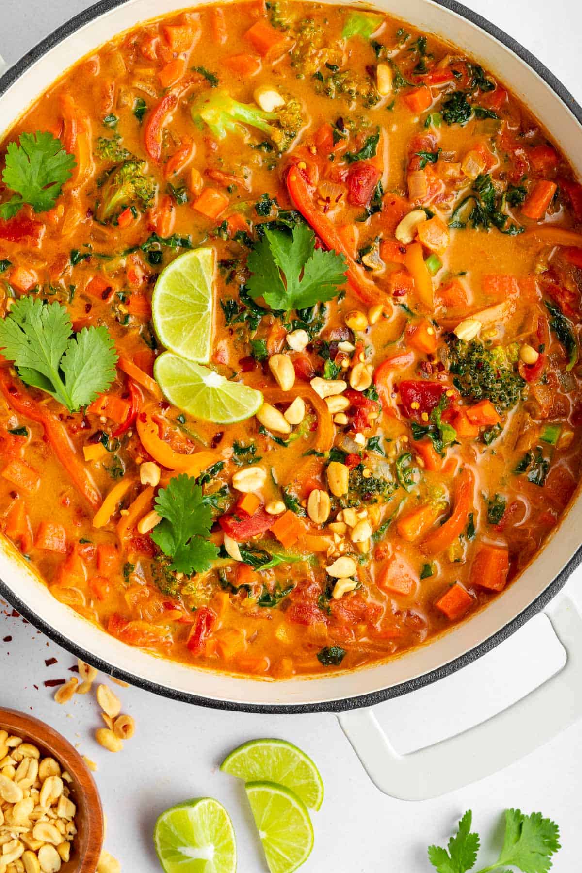 vegan thai red curry and white rice in a bowl alongside a wooden spoon and bowl of cilantro