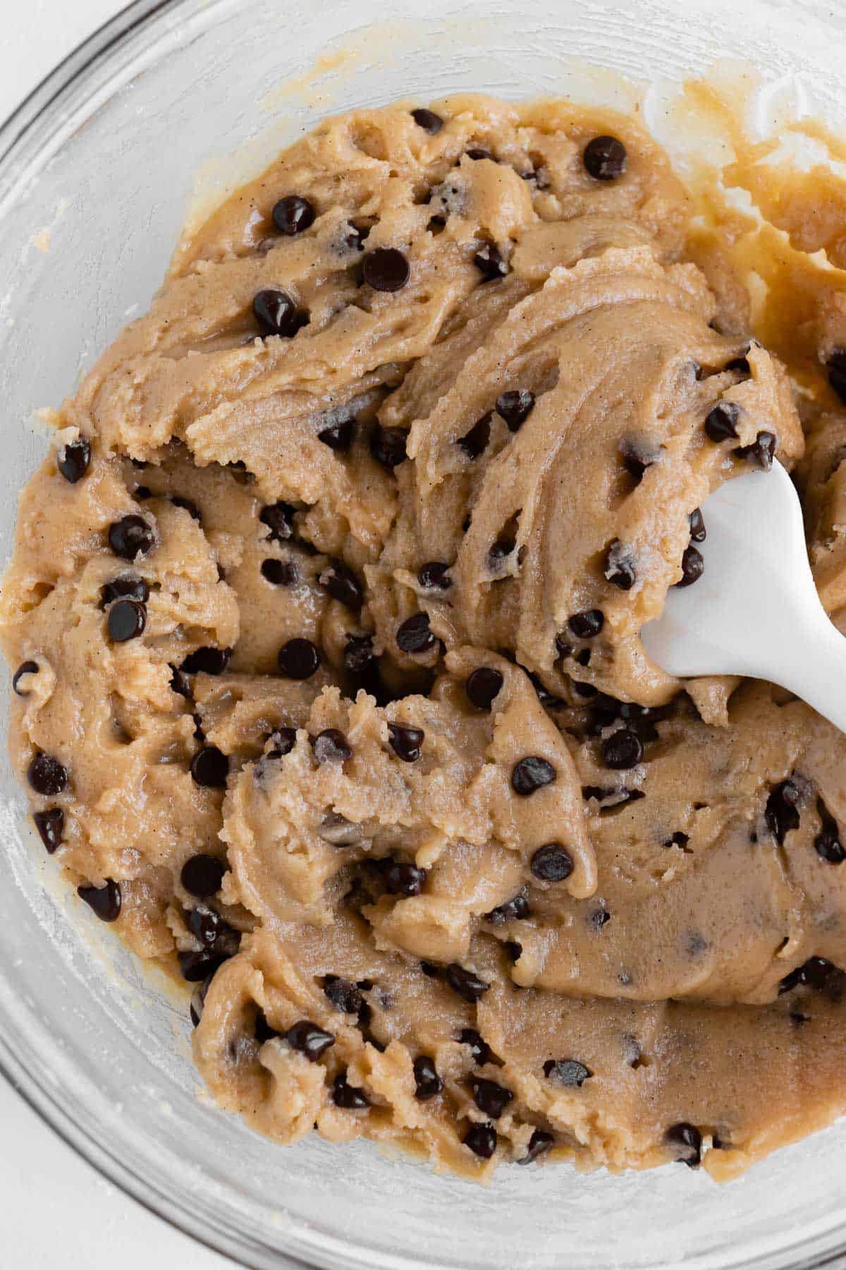 a white spatula scooping edible vegan cookie dough in a bowl