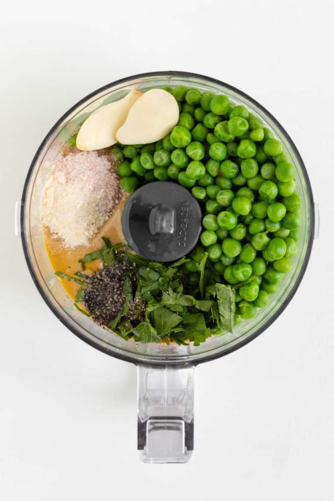 garlic, olive oil, tahini, salt, lemon juice, parsley, and peas inside a food processor