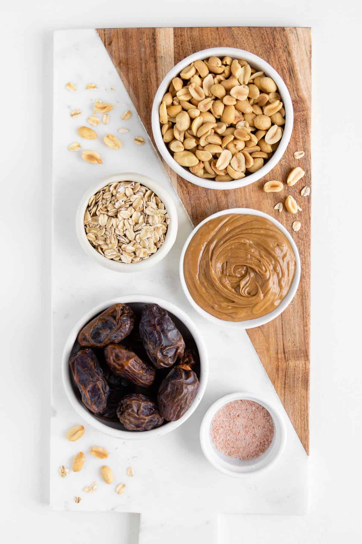 medjool dates, peanuts, oats, salt, and nut butter on a wooden marble cutting board