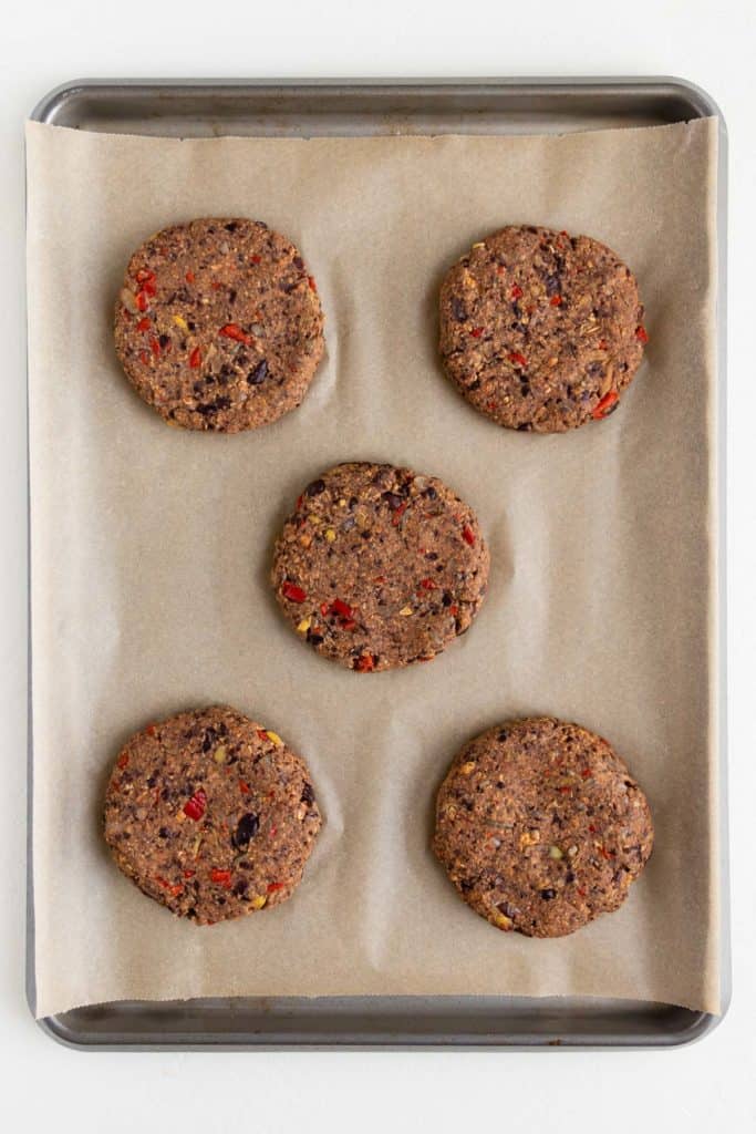 five vegan black bean burger patties on a baking sheet
