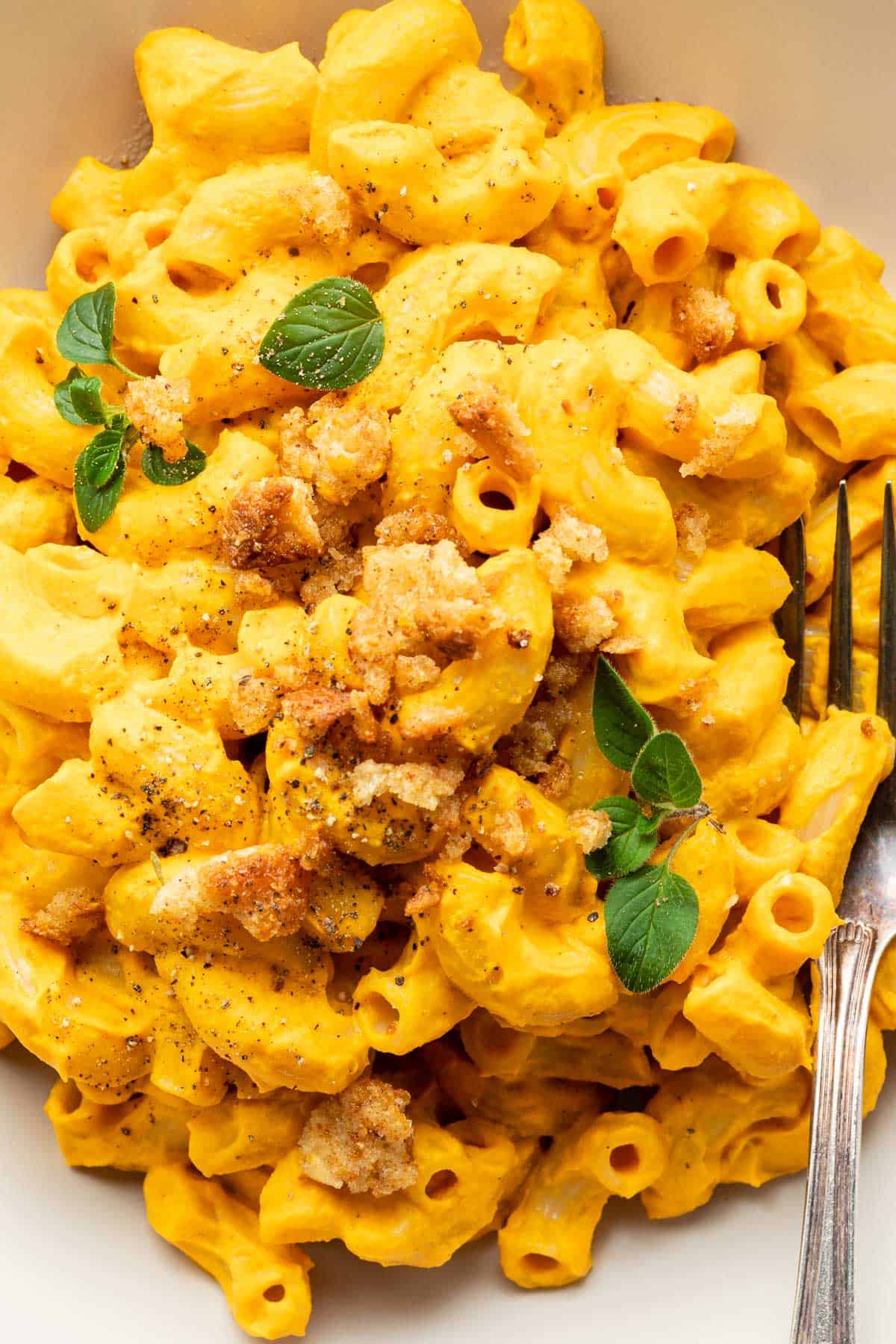 a bowl of vegan mac and cheese beside a bowl of cashews