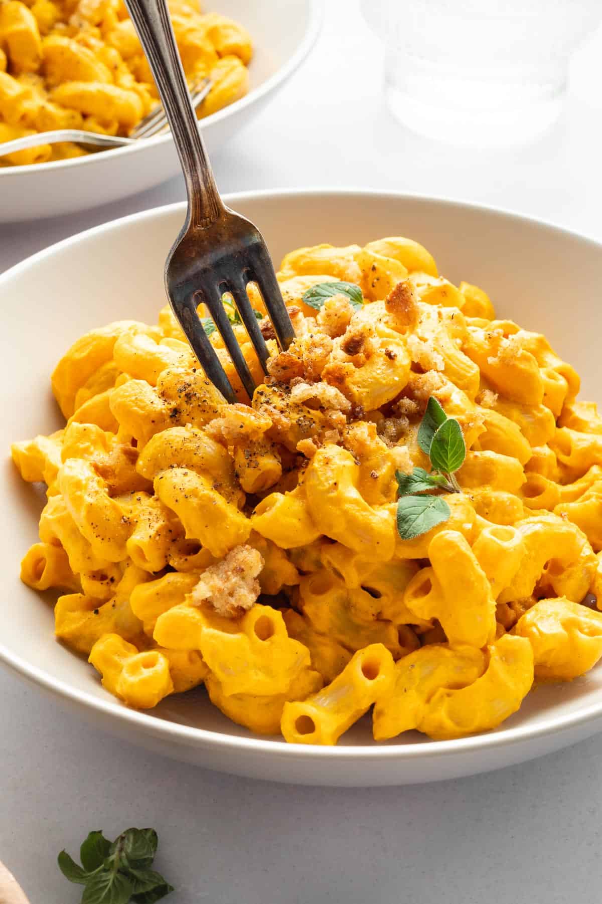 hands holding a white bowl filled with vegan mac and cheese