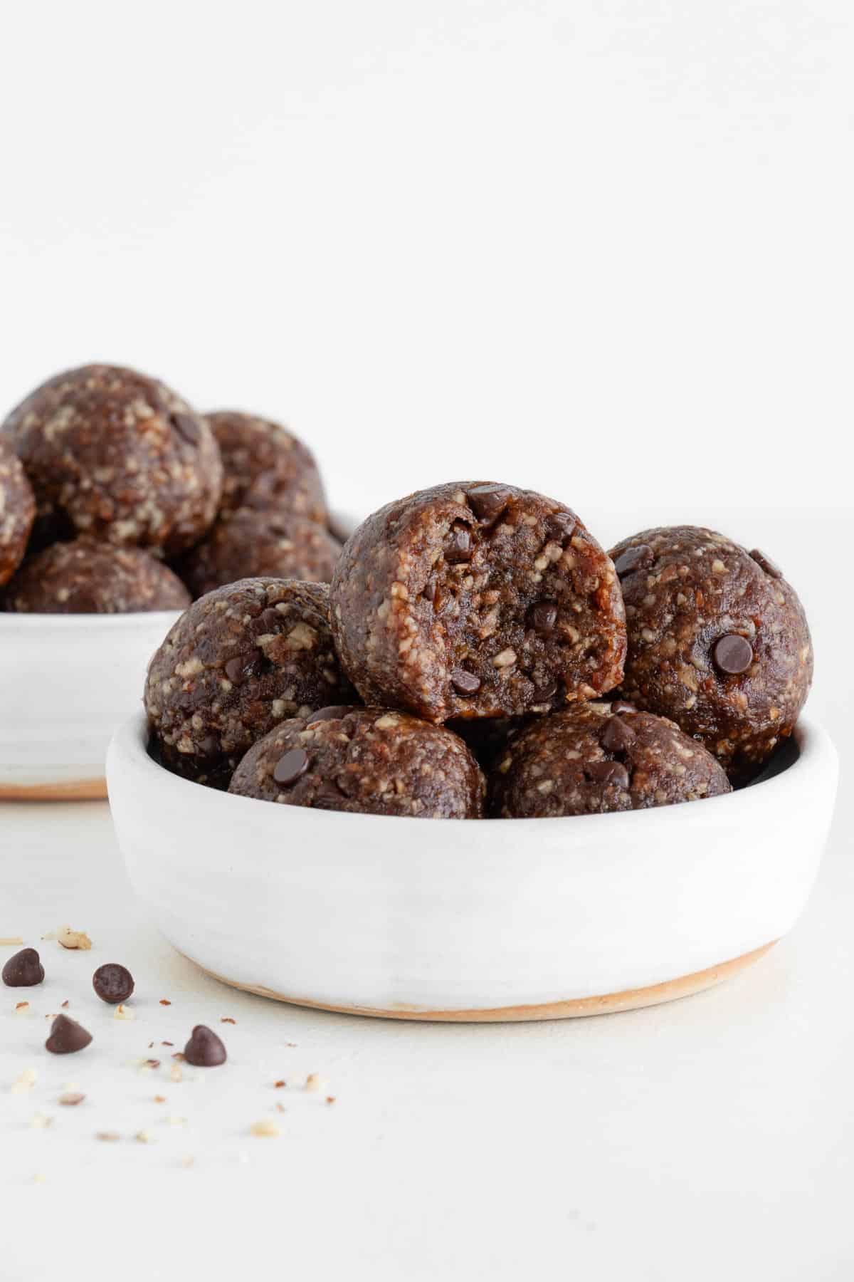 turtle energy balls stacked inside two small white bowls with a bite taken out of the center date ball