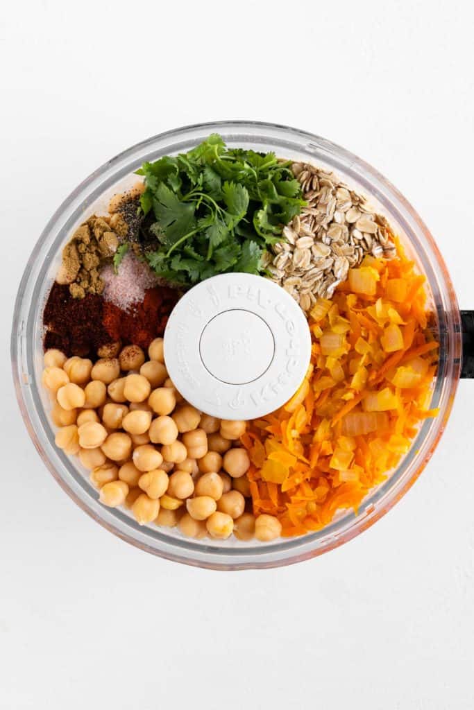 chickpeas, oats, grated carrots, diced onion, cilantro, and spices in a food processor bowl