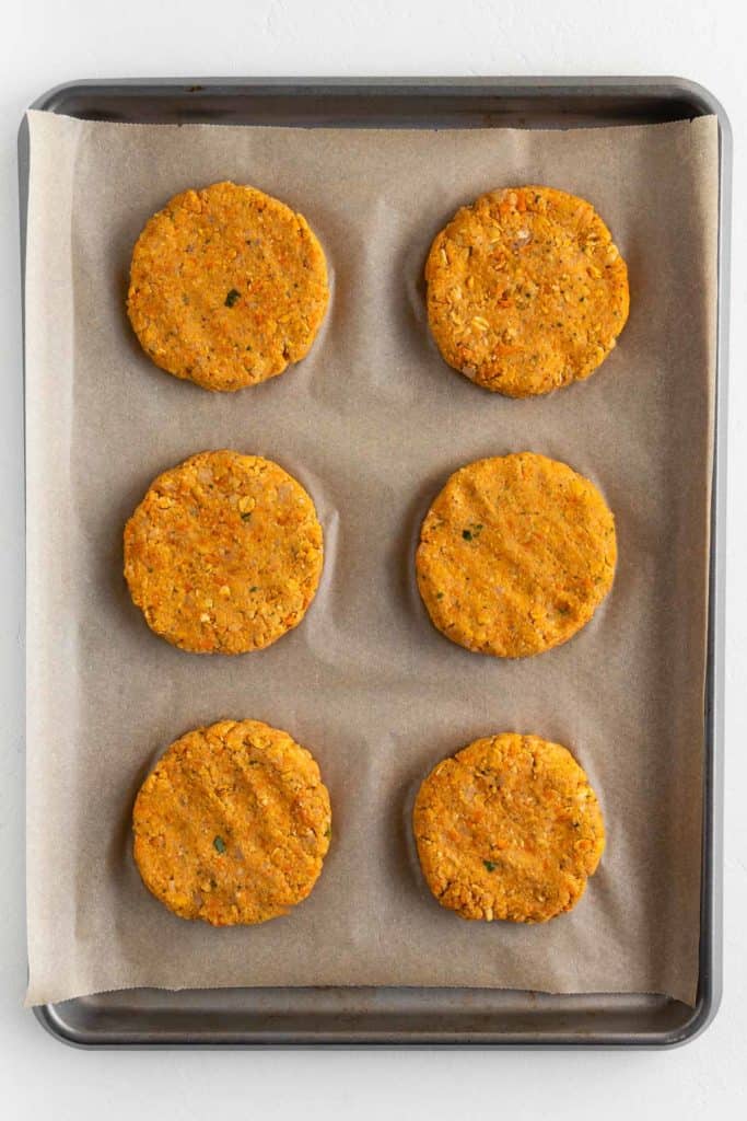 six uncooked vegan chickpea patties on a baking sheet