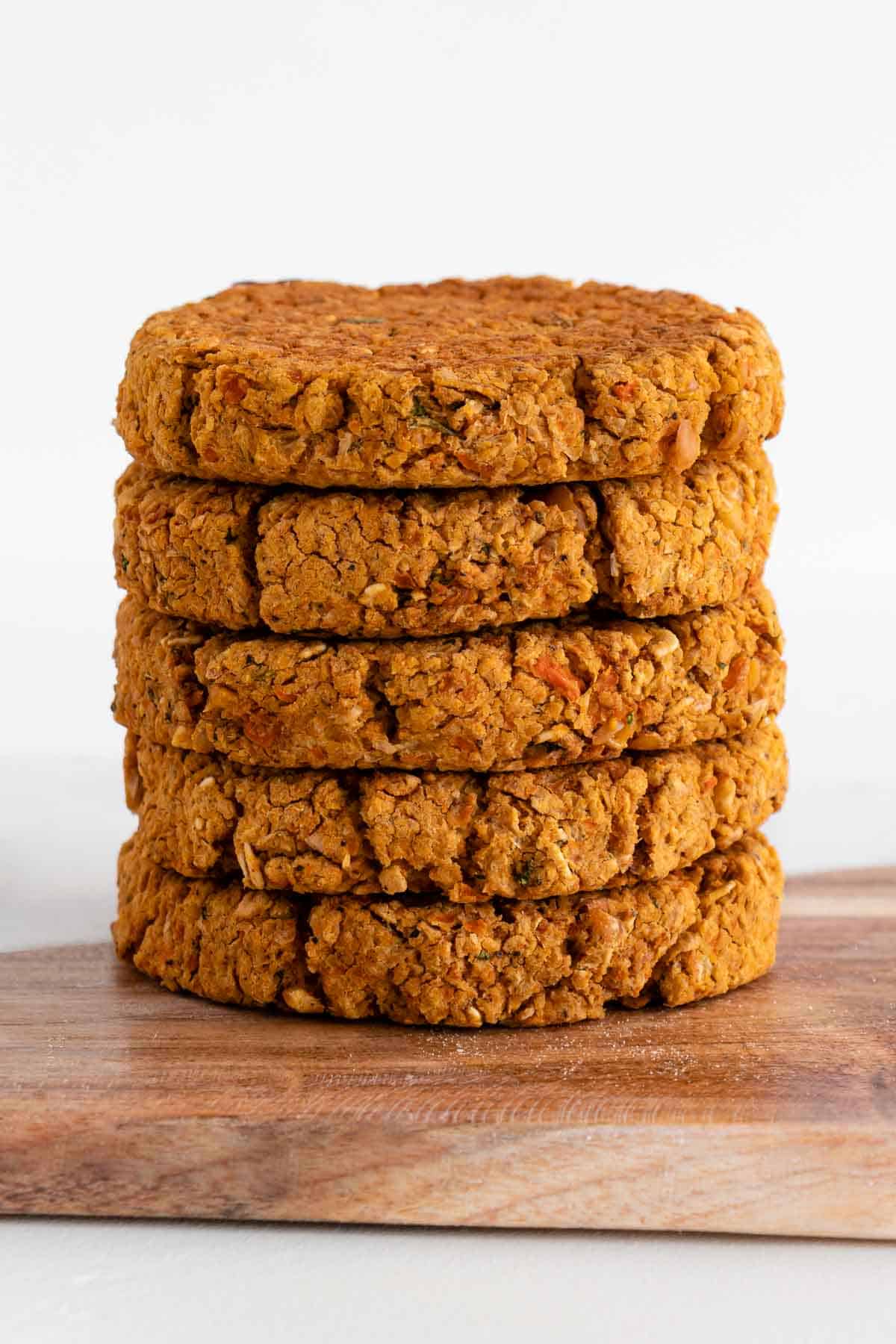 a stack of five chickpea burger patties on a wooden cutting board