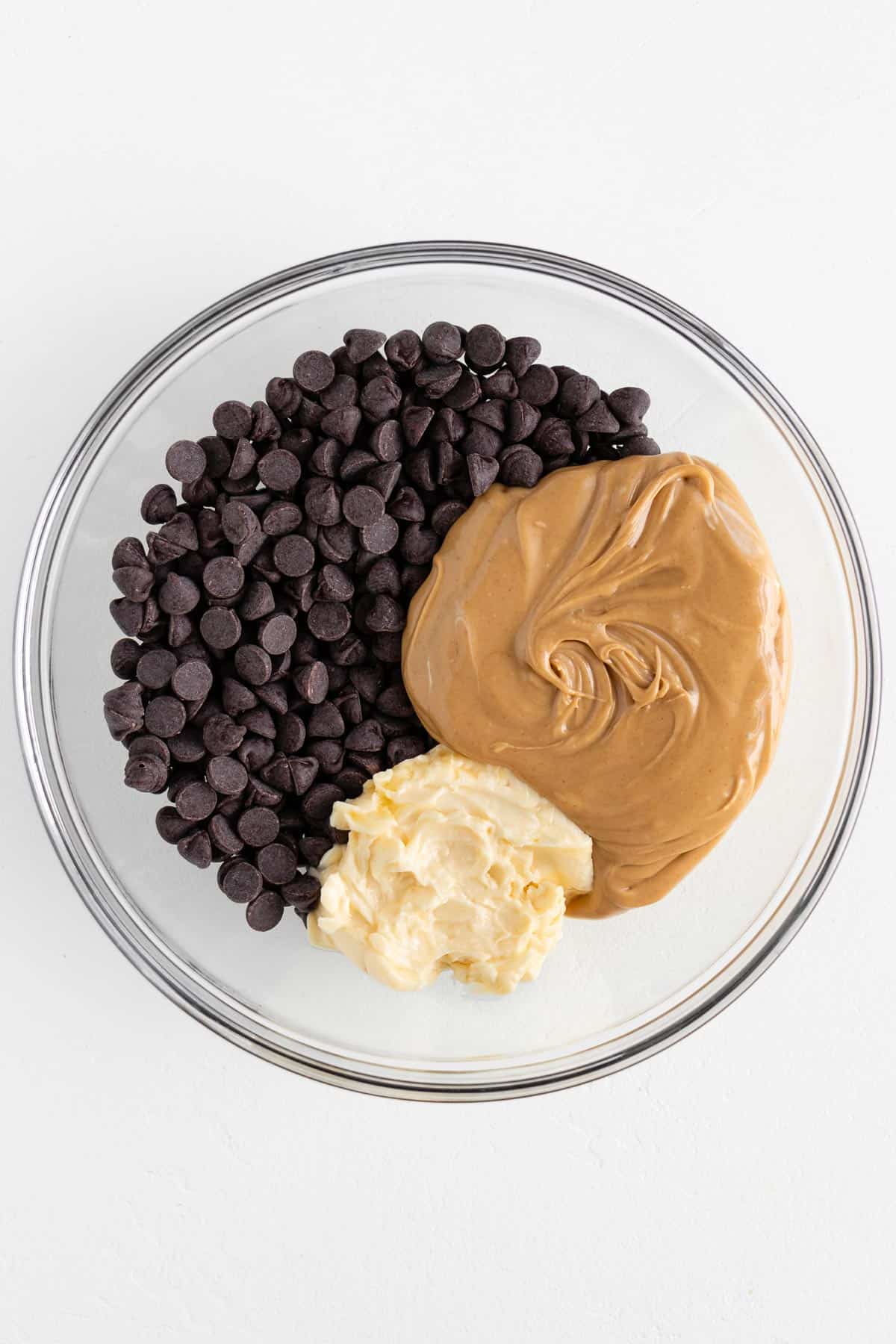 chocolate chips, vegan butter, and peanut butter inside a glass mixing bowl