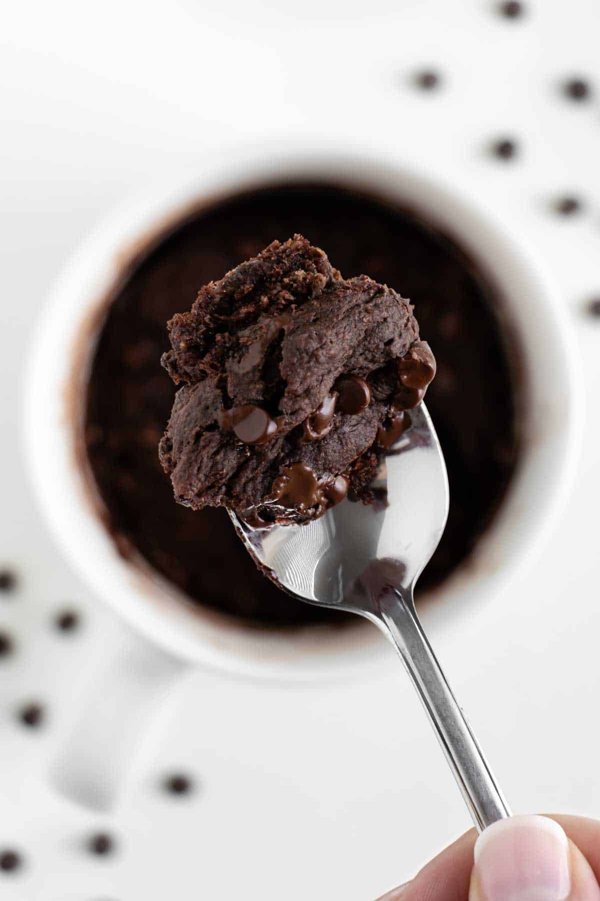 a spoon holding a scoop of a vegan chocolate banana mug cake