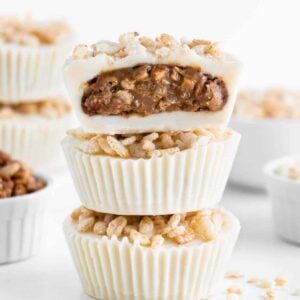 a stack of three crispy white chocolate almond butter cups with a bite taken out of the top one