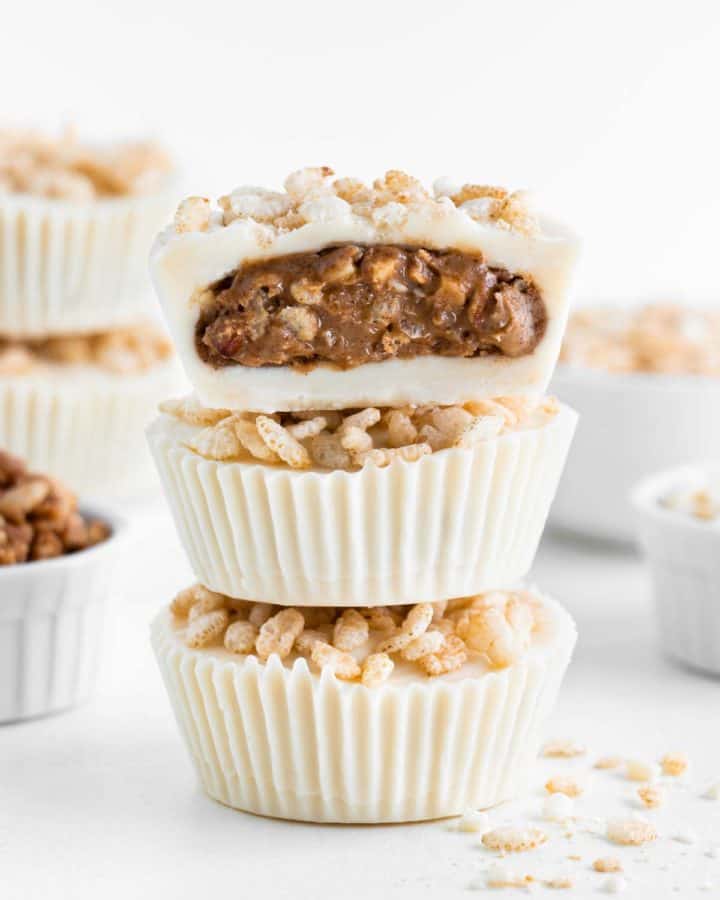 a stack of three crispy white chocolate almond butter cups with a bite taken out of the top one