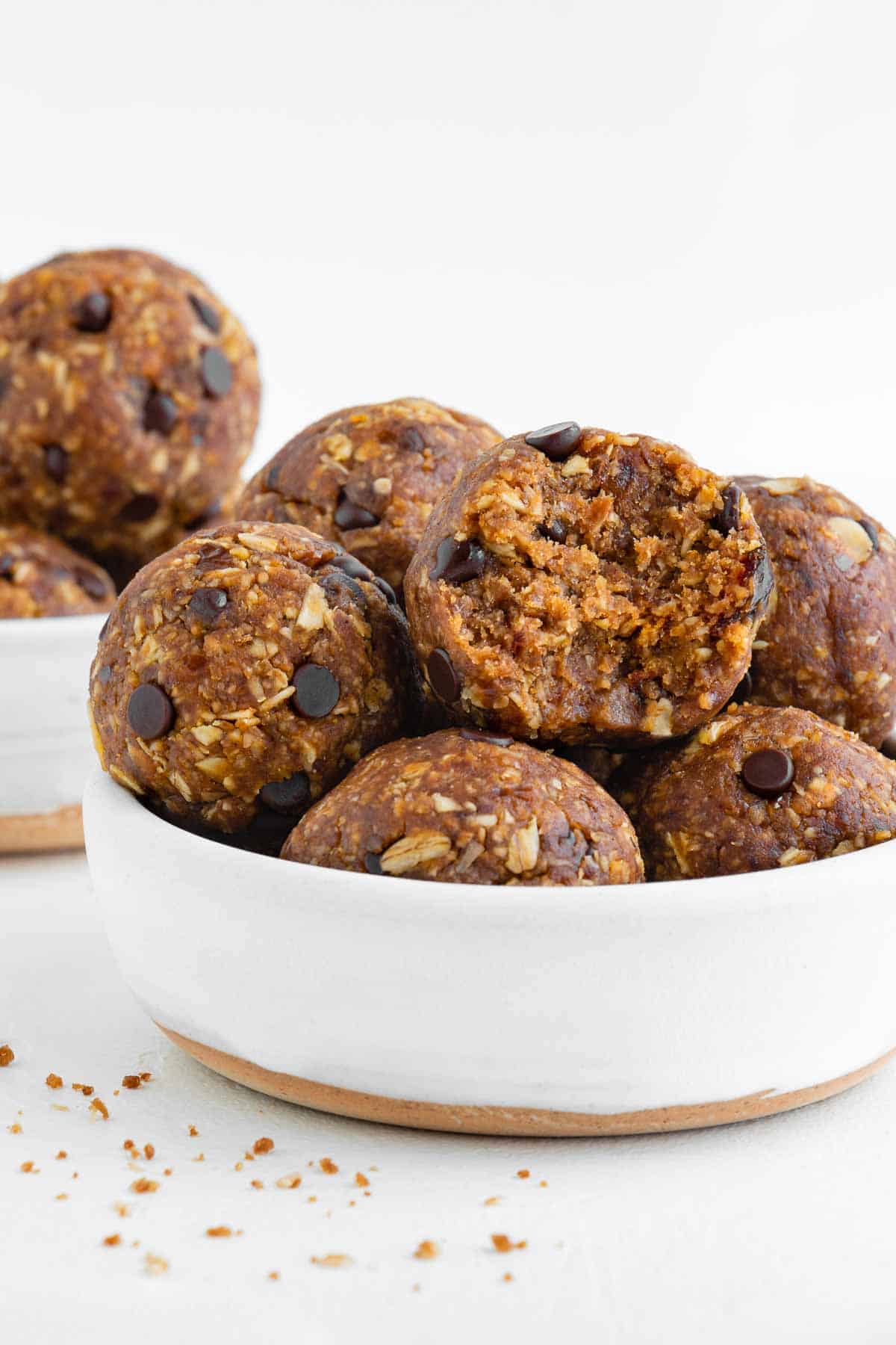 pumpkin spice balls stacked inside a white bowl with a bite taken out of the middle ball