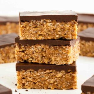 three vegan scotcheroos stacked on top of each other, surrounded by more vegan special k bars