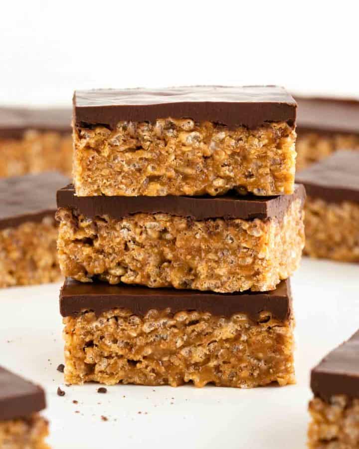 three vegan scotcheroos stacked on top of each other, surrounded by more vegan special k bars