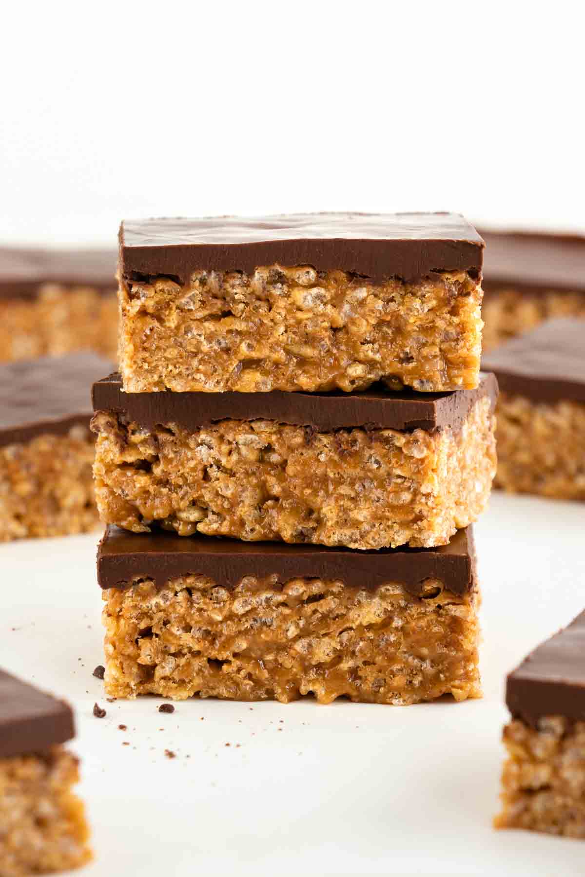 three vegan scotcheroos stacked on top of each other, surrounded by more vegan special k bars