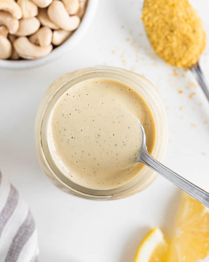 a spoon scooping into a jar of vegan cashew cream sauce