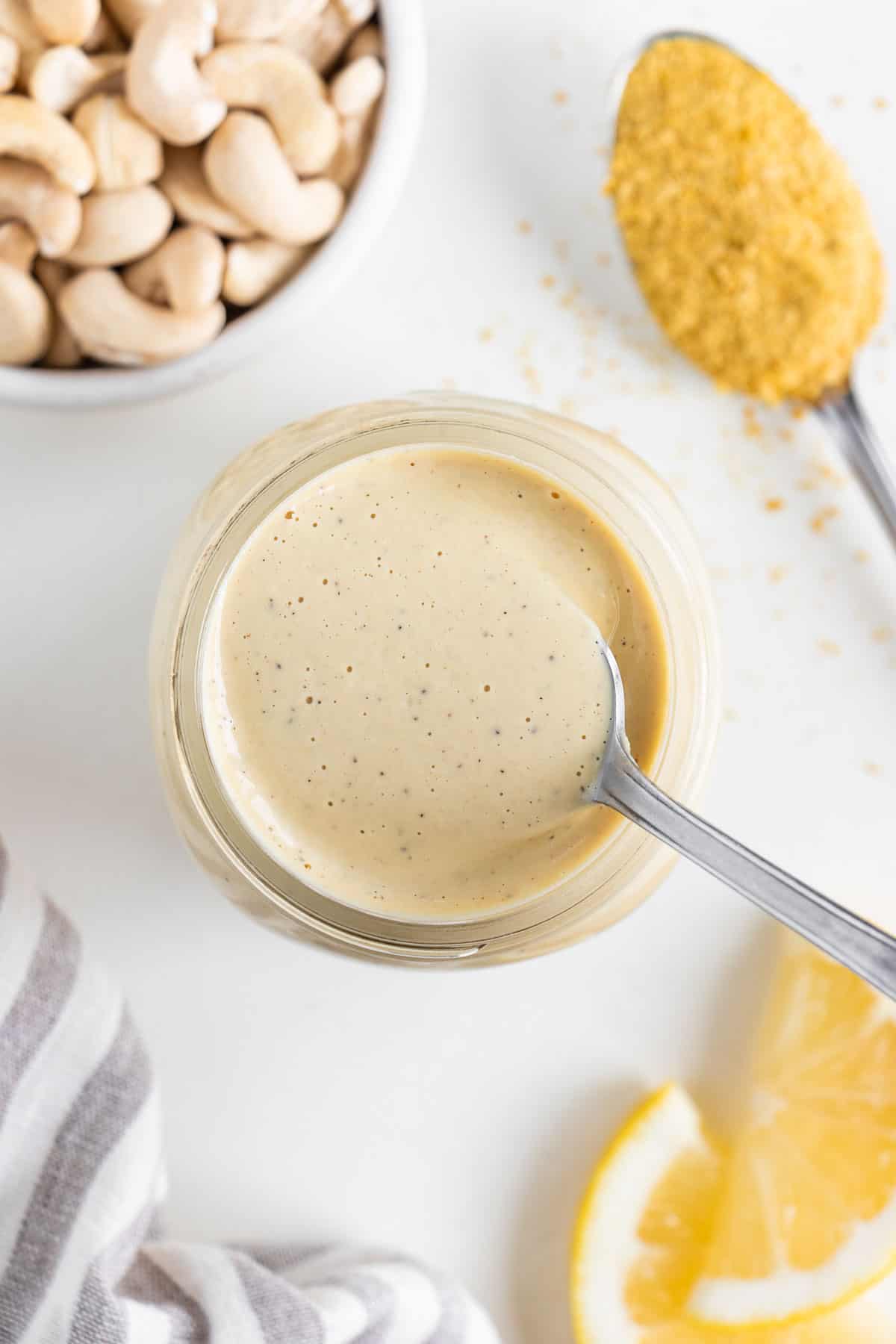 a spoon scooping into a jar of vegan cashew cream sauce