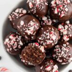 vegan chocolate peppermint truffles inside a white bowl with a bite taken out of one truffle