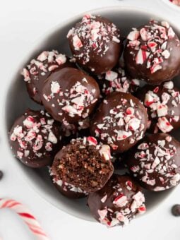 vegan chocolate peppermint truffles inside a white bowl with a bite taken out of one truffle