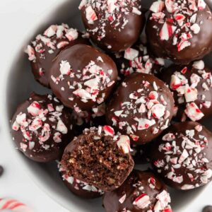 vegan chocolate peppermint truffles inside a white bowl with a bite taken out of one truffle