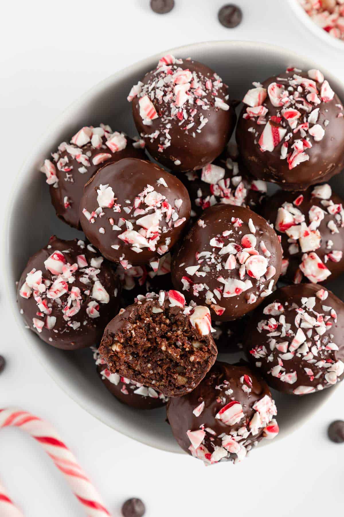 vegan chocolate peppermint truffles inside a white bowl with a bite taken out of one truffle