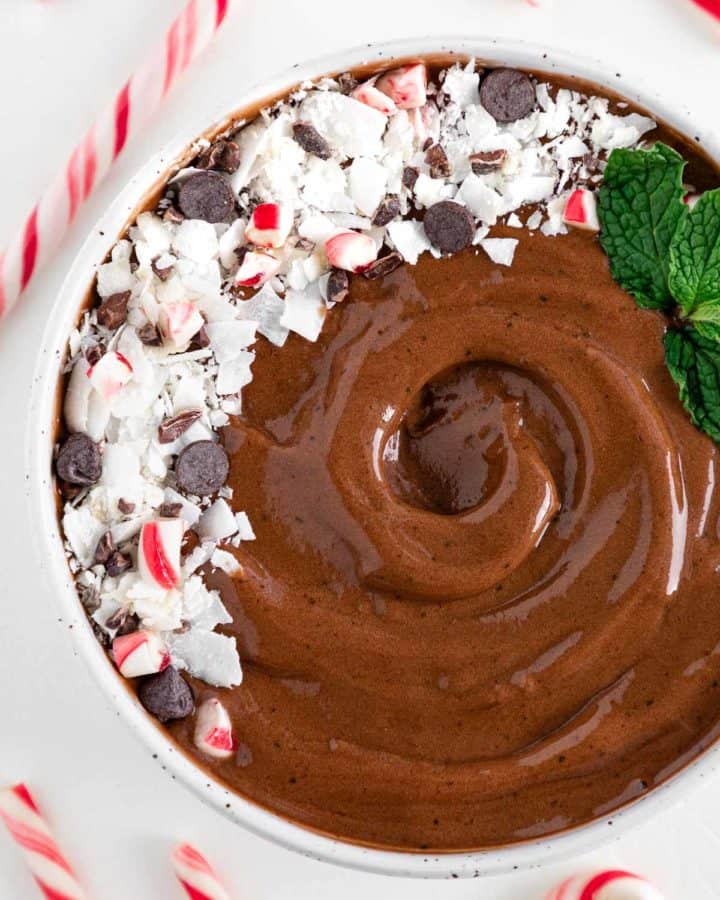 a chocolate peppermint smoothie bowl surrounded by candy canes