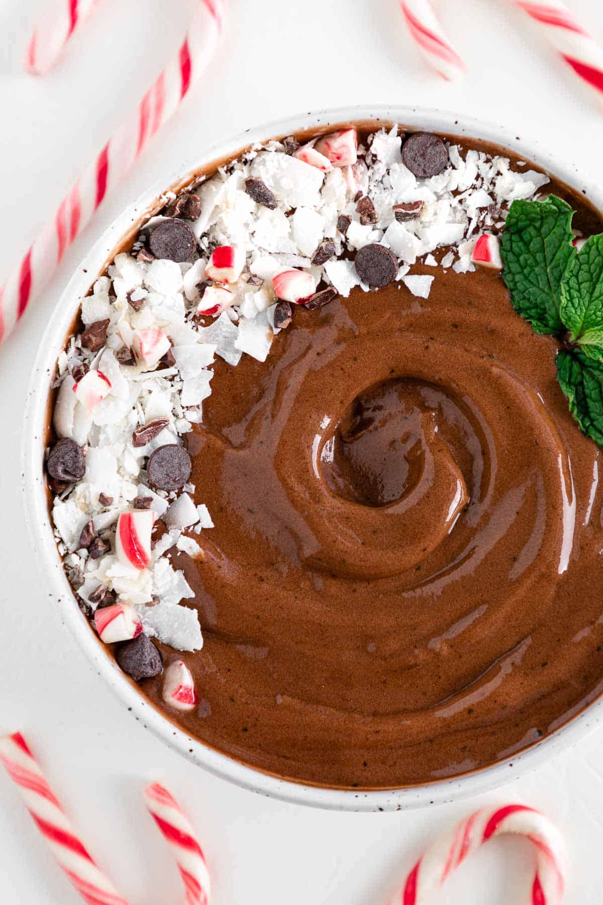 a chocolate peppermint smoothie bowl surrounded by candy canes