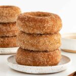 a stack of three vegan cinnamon sugar donuts on a small white ceramic plate