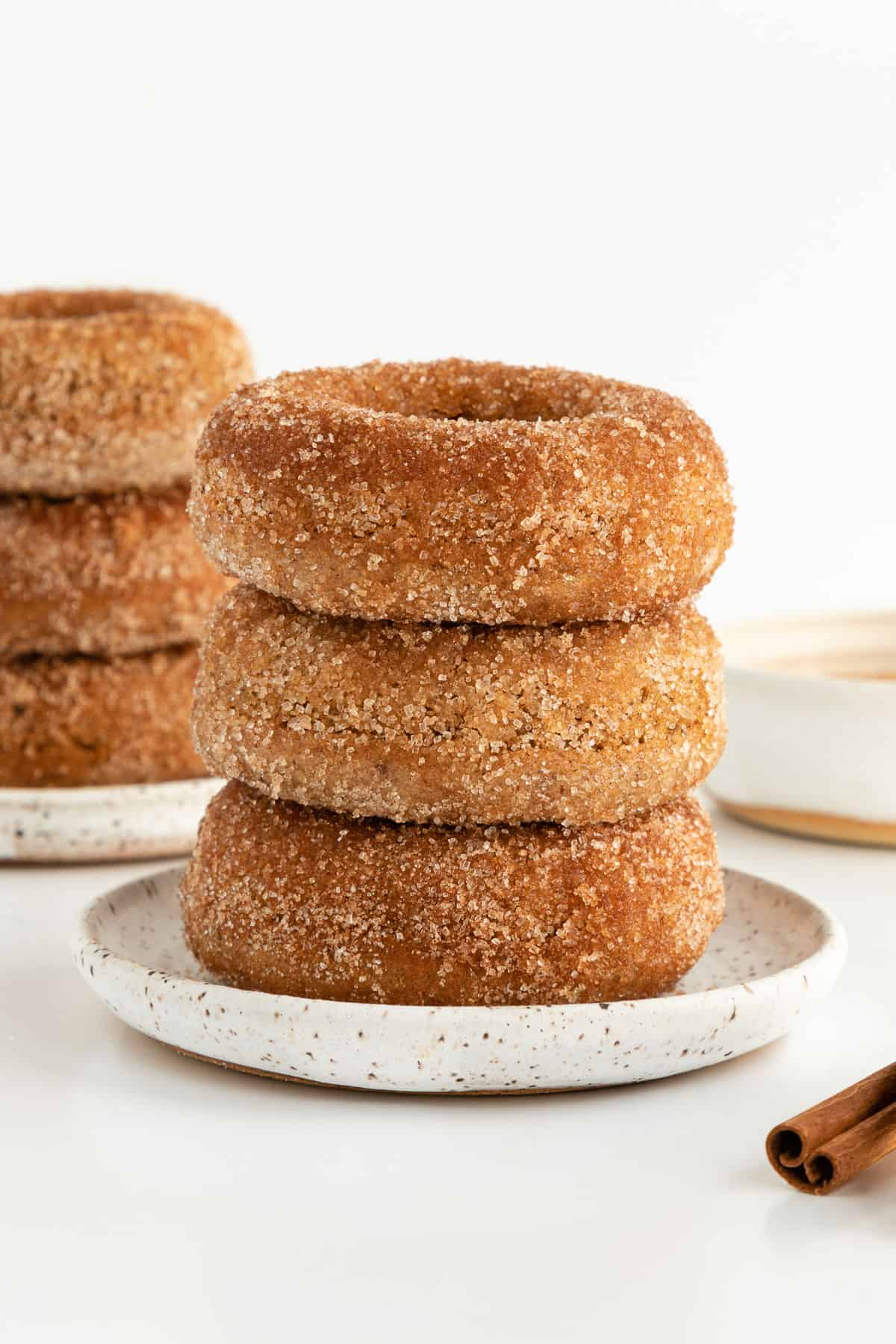 a stack of three vegan cinnamon sugar donuts on a small white ceramic plate