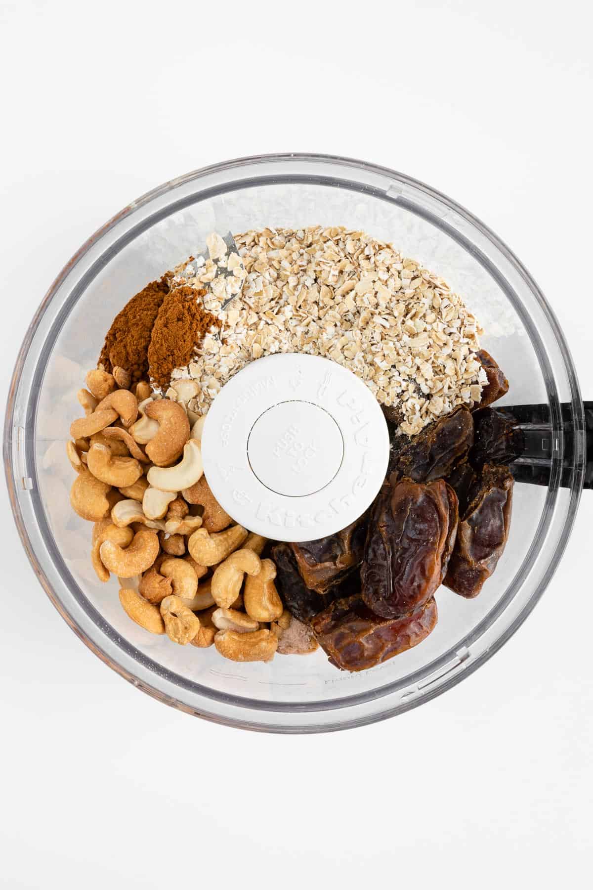 cashews, dates, oats, cinnamon, and vanilla extract inside the bowl of a food processor