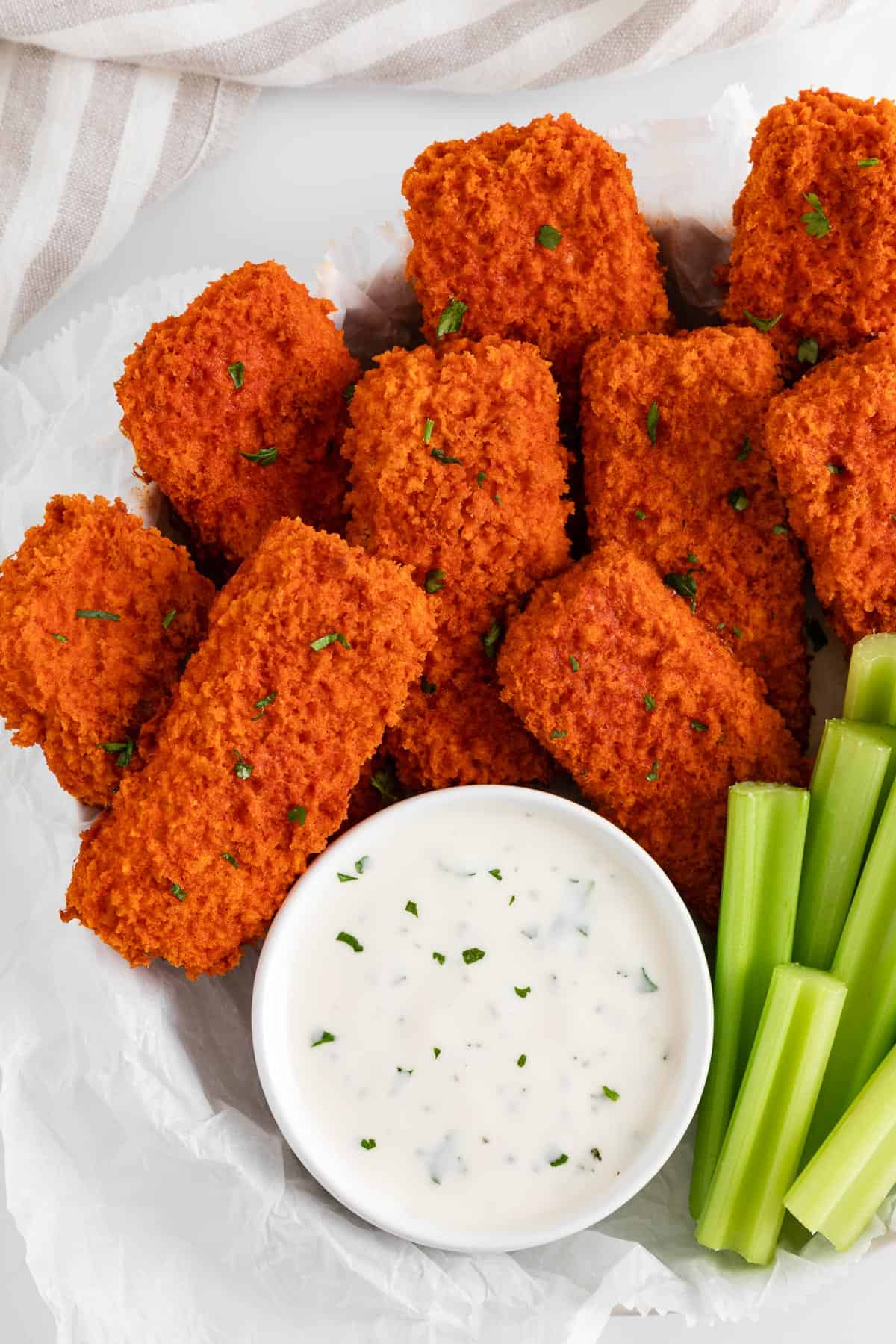 vegan buffalo tofu wings spread on a plate with celery and ranch dressing