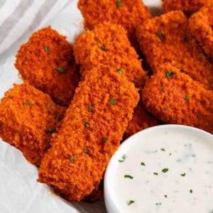 a white plate filled with a stack of vegan buffalo tofu wings and a bowl of ranch dressing