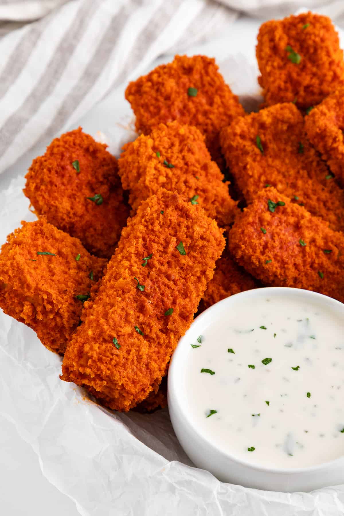 a white plate filled with a stack of vegan buffalo tofu wings and a bowl of ranch dressing