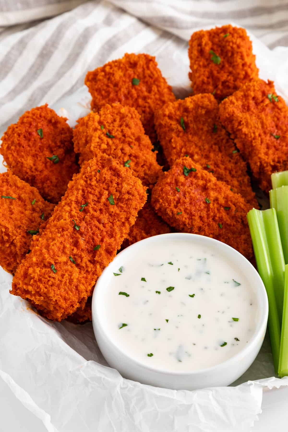 vegan buffalo tofu wings spread on a plate with celery and ranch dressing