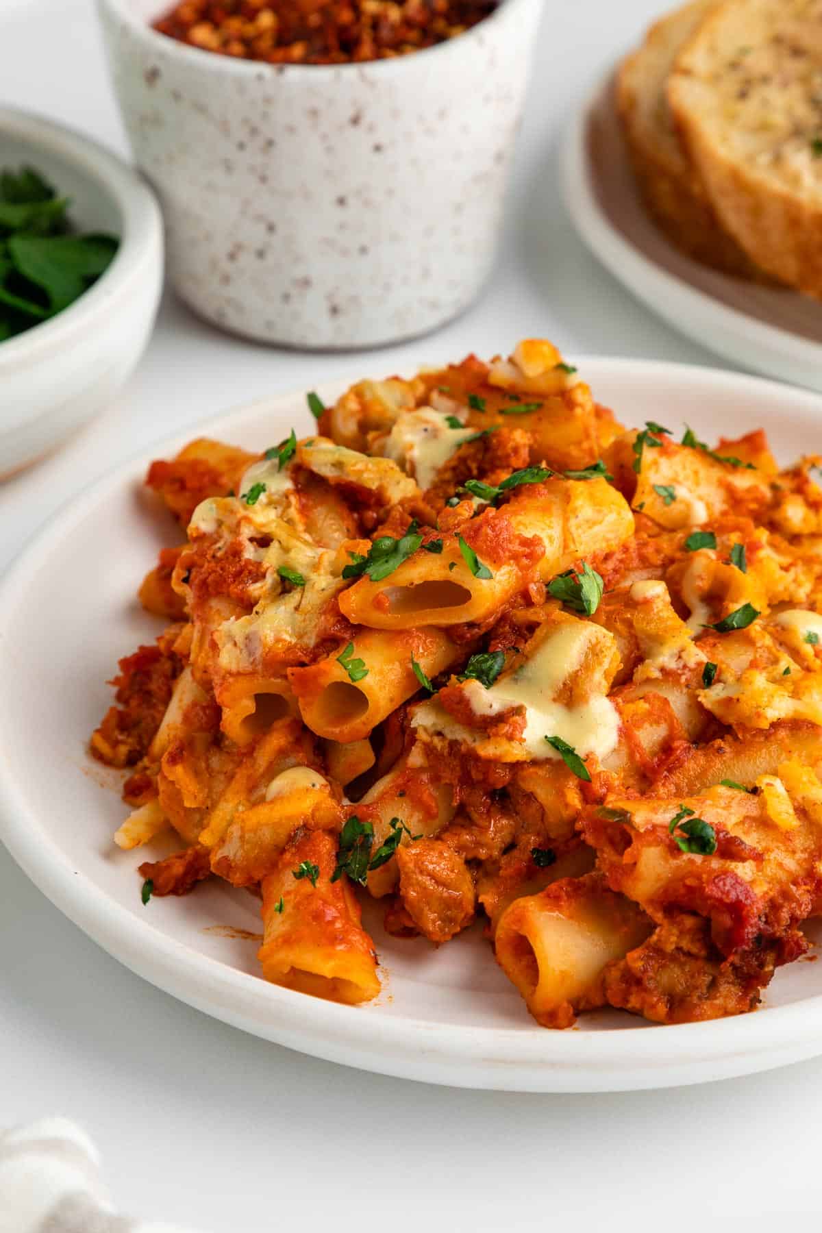 a close up image of vegan baked ziti on a white plate