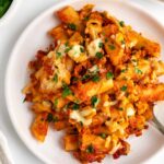 a close up image of vegan baked ziti on a white plate