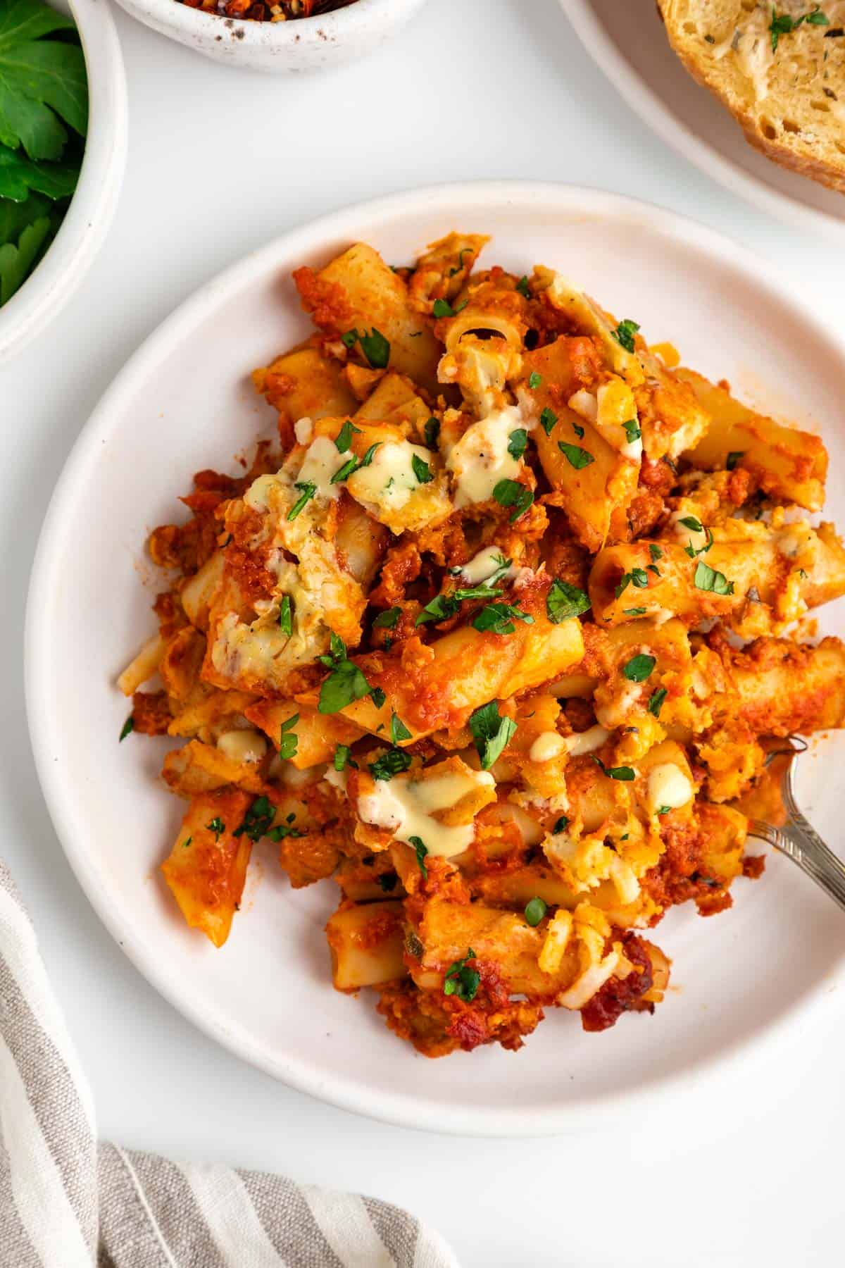 a close up image of vegan baked ziti on a white plate