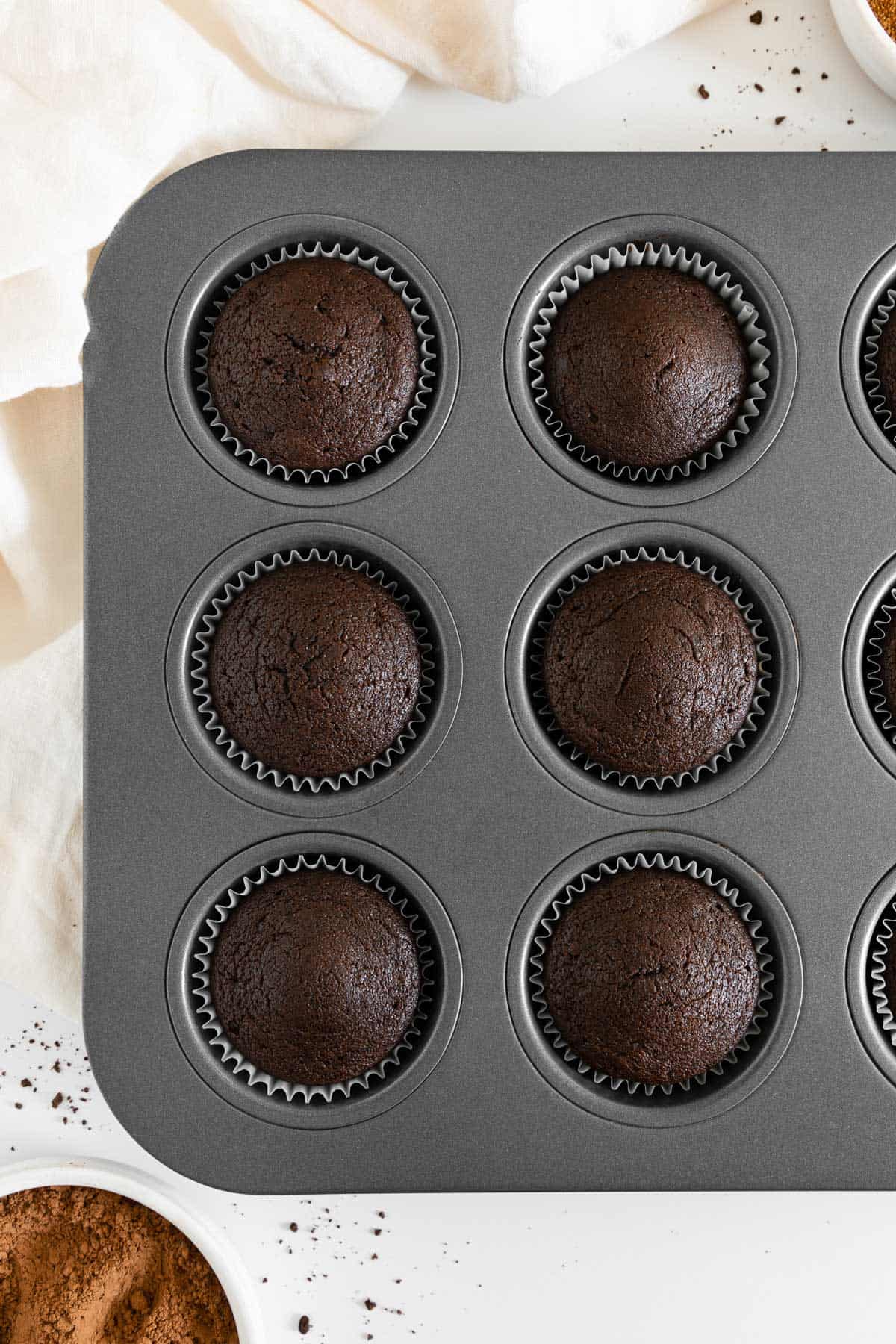 vegan chocolate cupcakes freshly baked inside a muffin tin