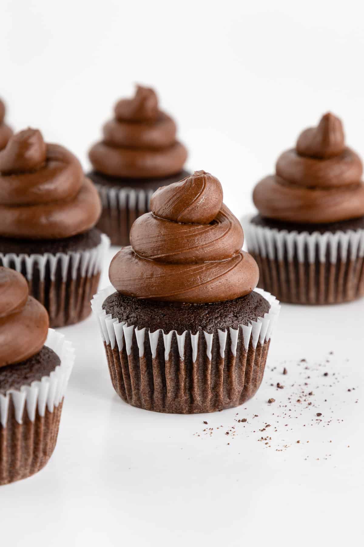 five vegan chocolate cupcakes with chocolate buttercream frosting on top