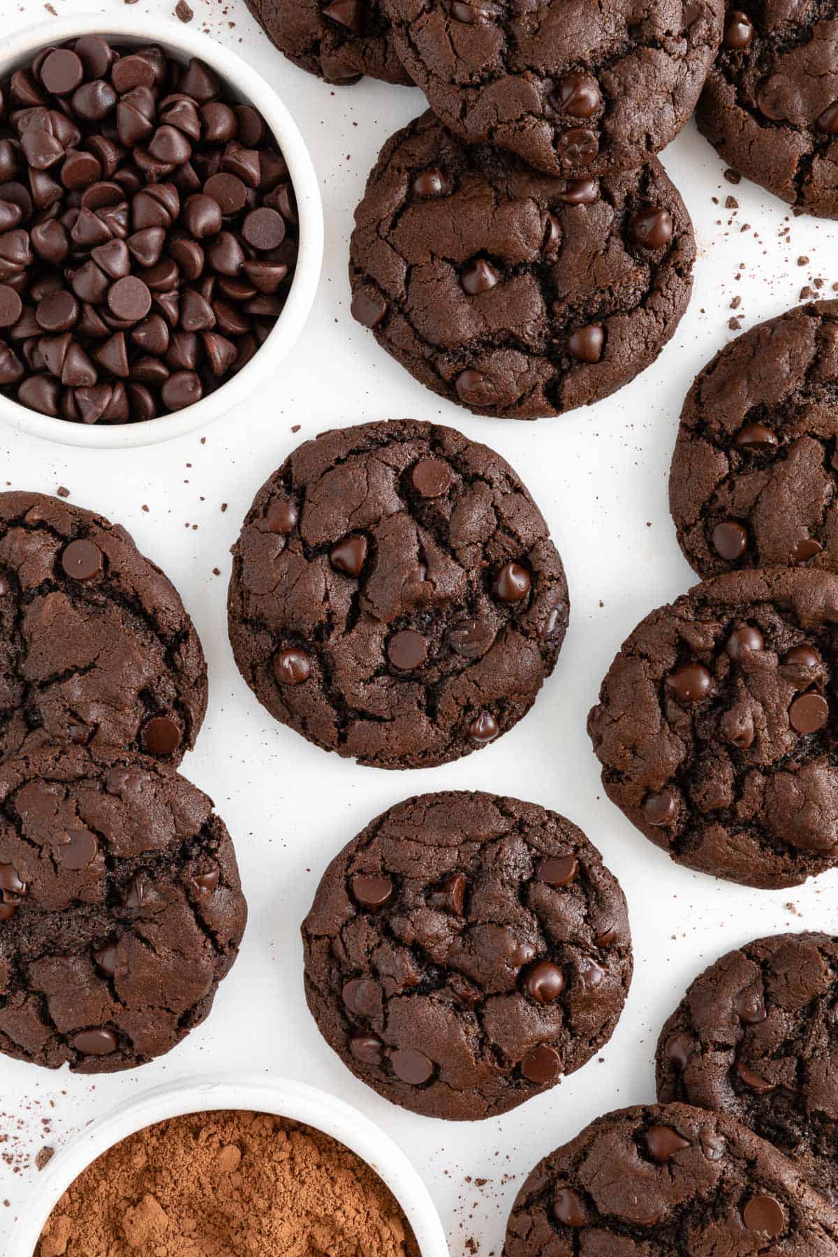 several warm and gooey vegan double chocolate chip cookies laying on white parchment paper